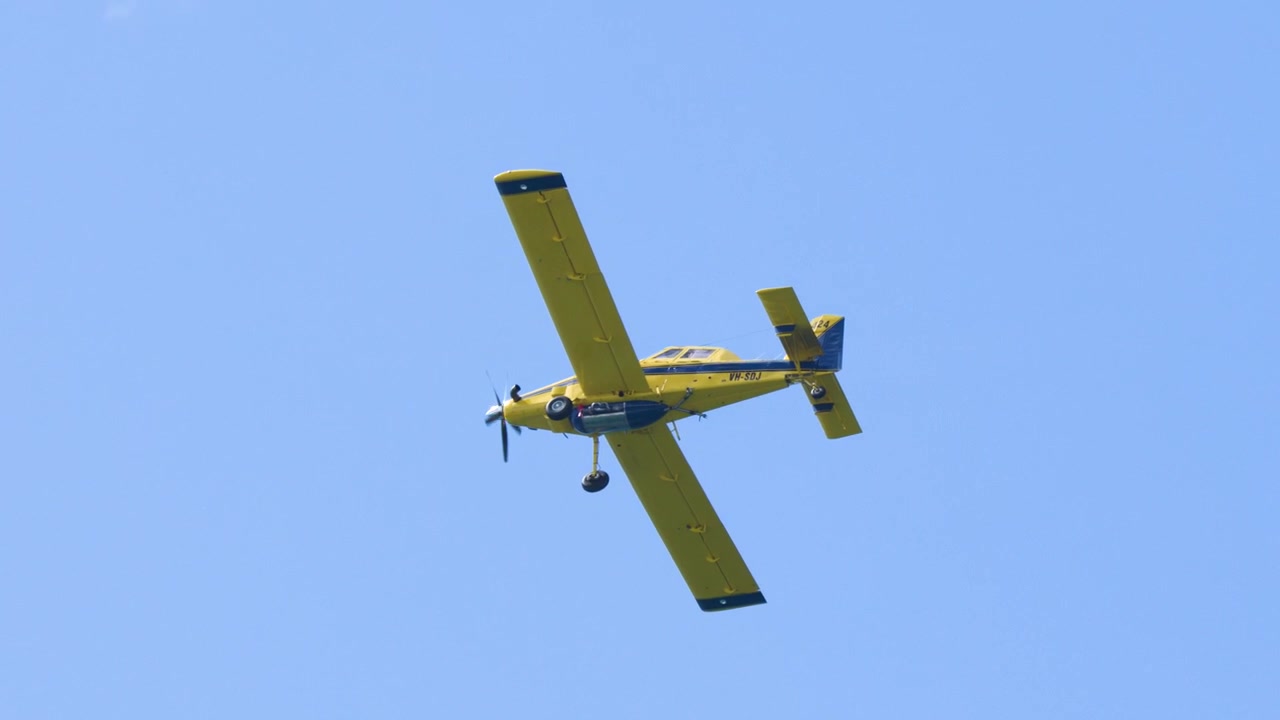 Un aereo utilitario giallo effettua un volo stabile attraverso cieli azzurri e sereni in Australia.