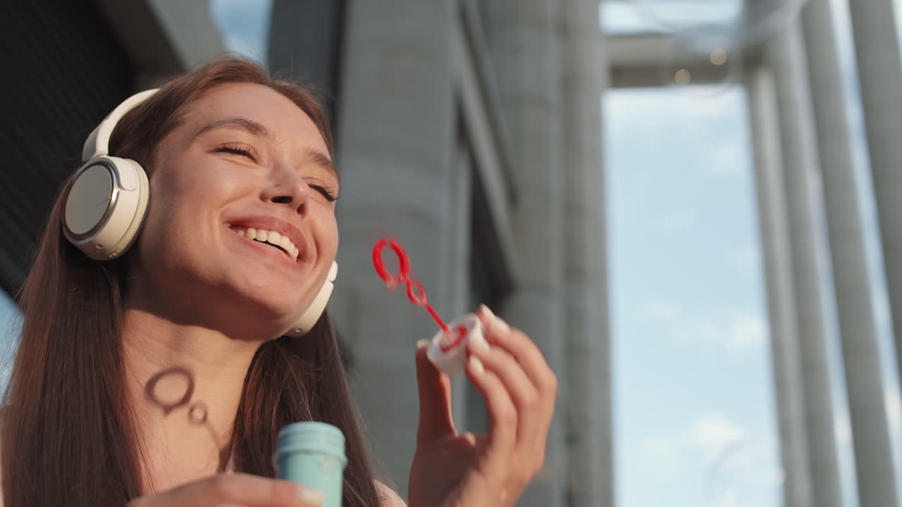 Woman in Headphones Blowing Soap Bubbles