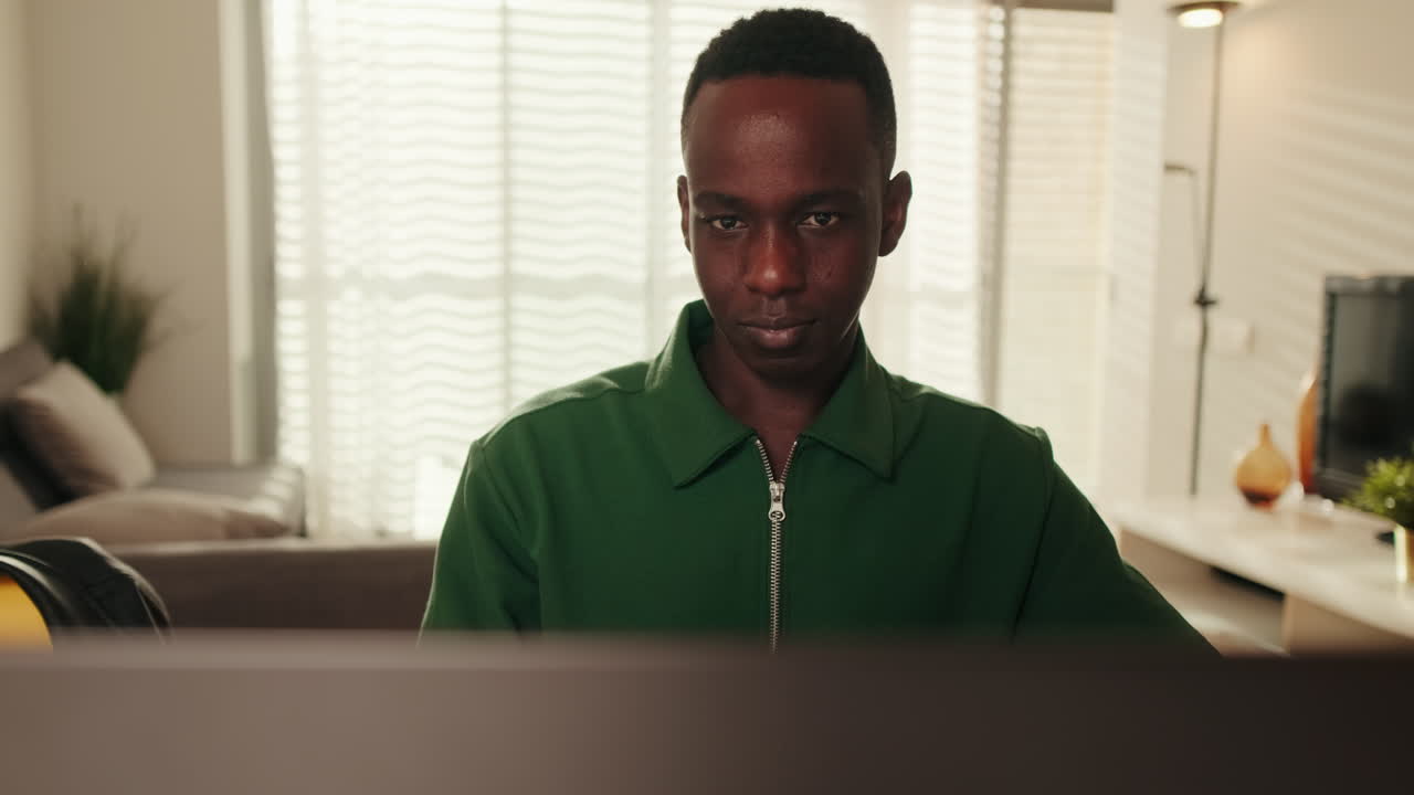 Young African Man Concentrating on Laptop Screen at Home