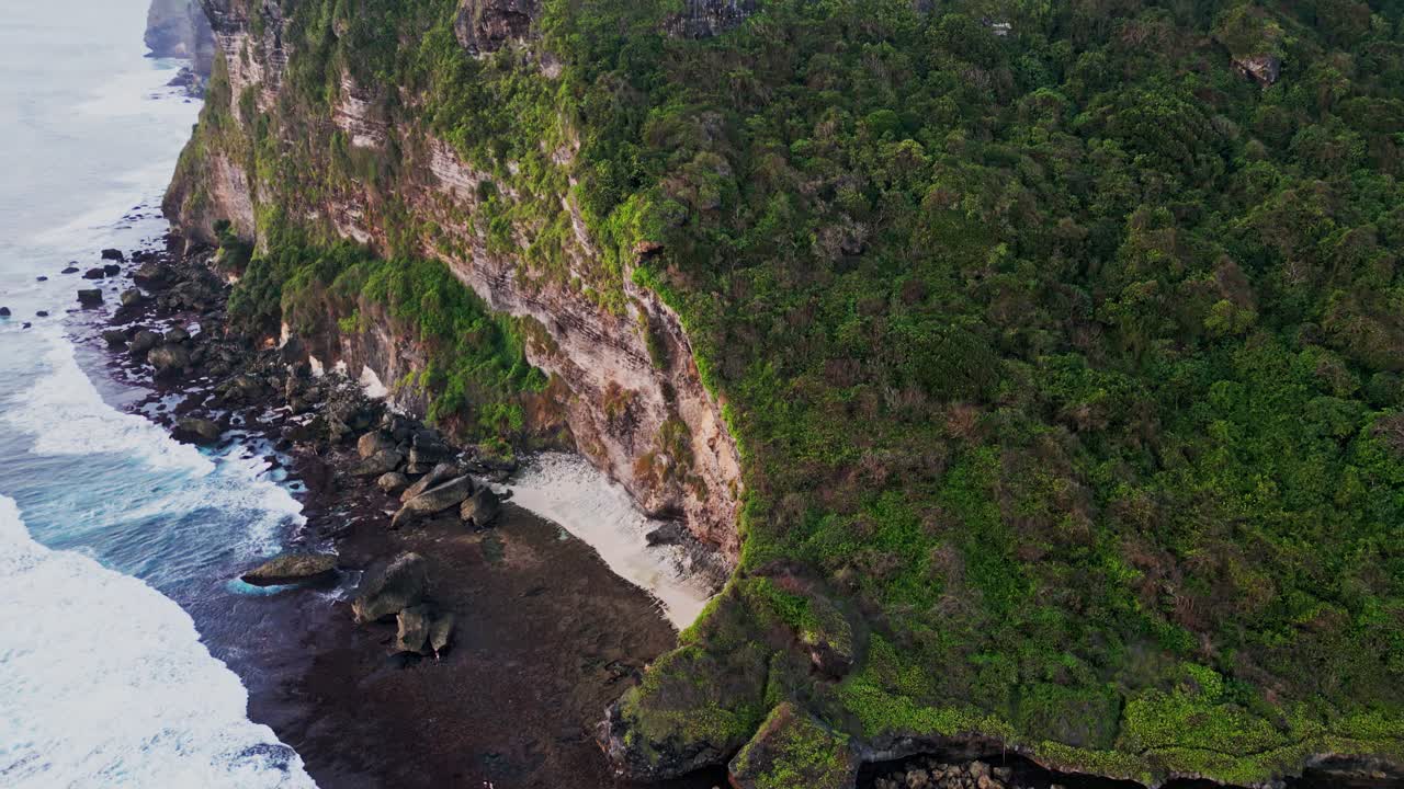 Drone footage glides over Nyang Nyang Beach in Uluwatu, highlighting the remote location, wide sandy shore, and natural cliffs that frame this quiet and untouched paradise in tropical Bali