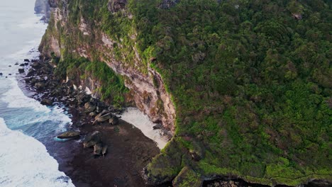 drone footage glides over nyang nyang beach in uluwatu, highlighting the remote location, wide sandy shore, and natural cliffs that frame this quiet and untouched paradise in tropical bali