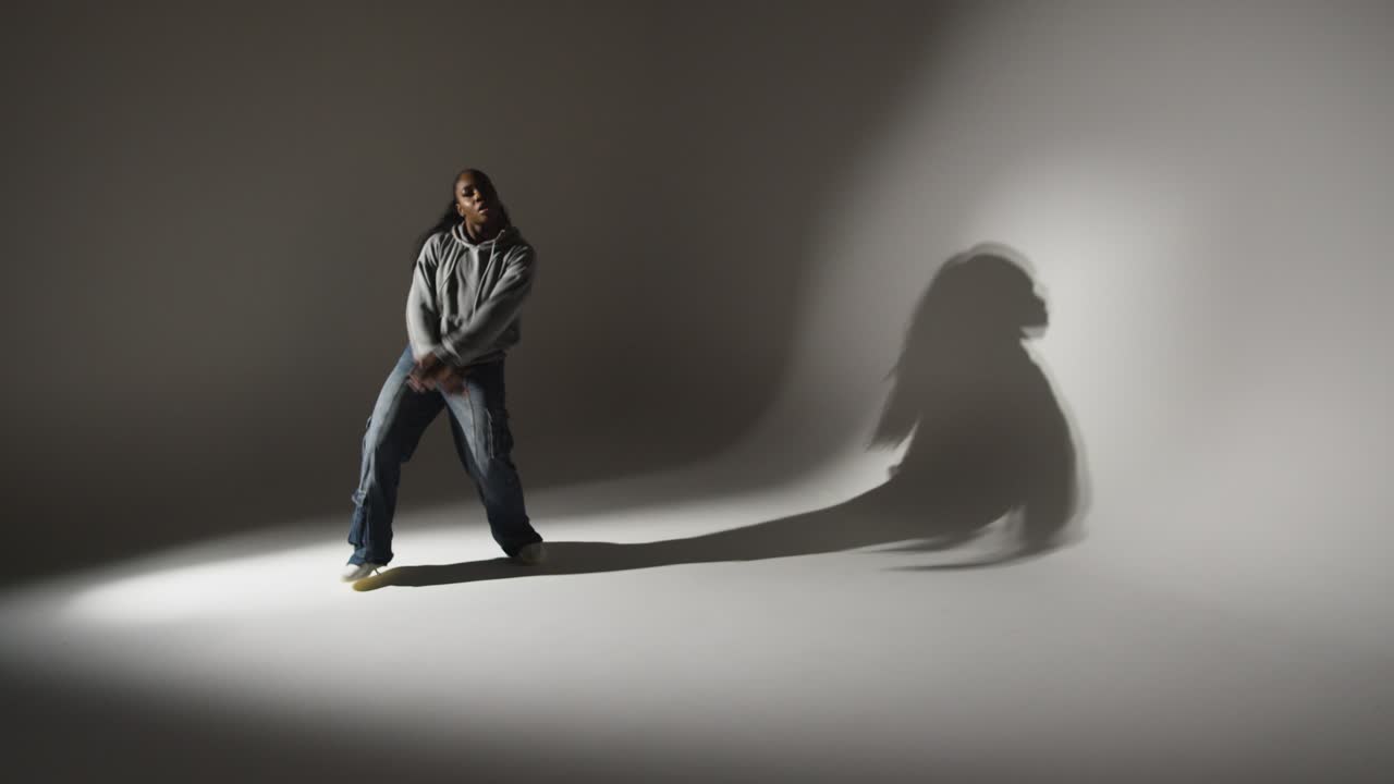 회색 배경에 낮은 키 조명과 함께 그림자를 던지는 춤을 추는 젊은 여성의 전체 길이 스튜디오 초상화  ⁇  3