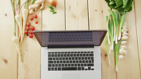 video de verduras frescas alrededor de una computadora portátil con fondo de madera