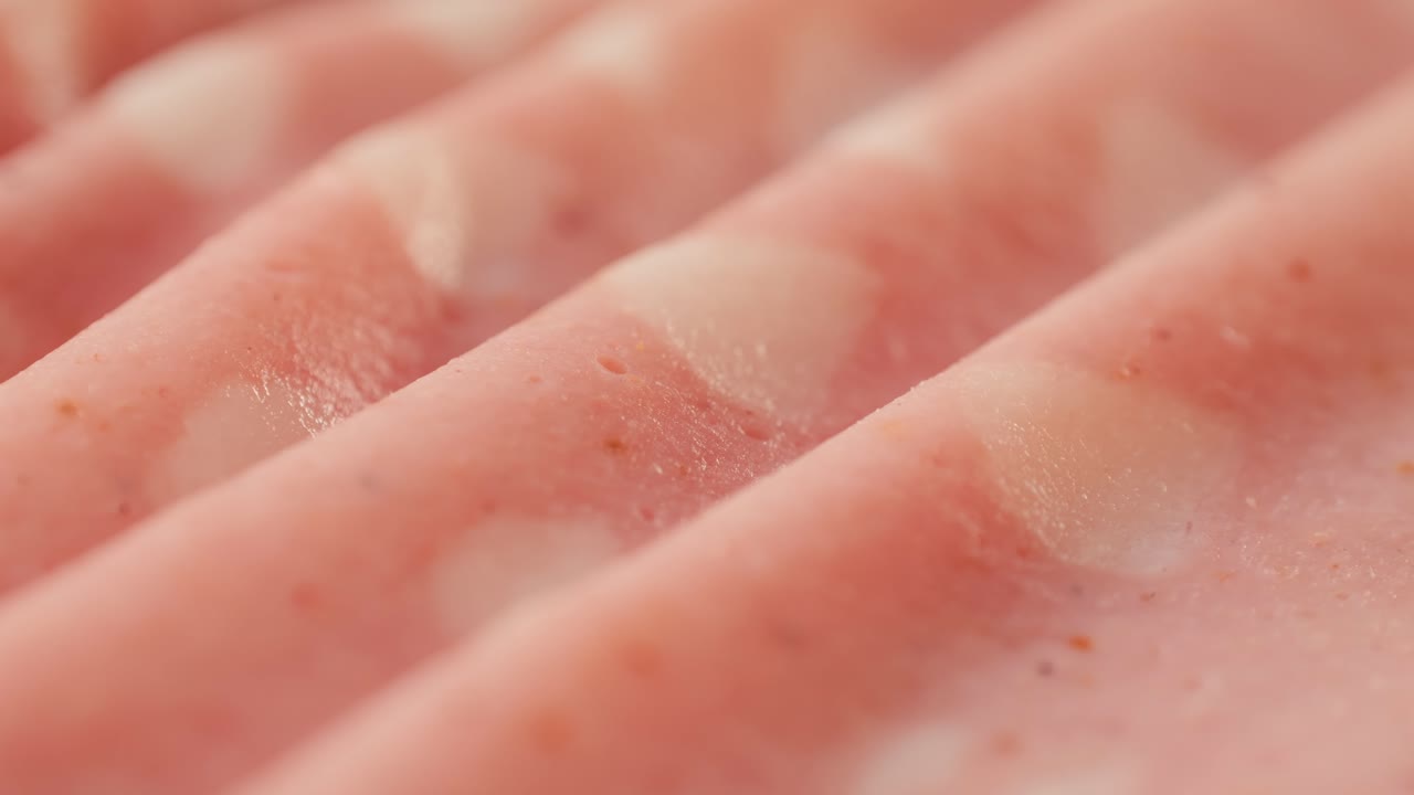 Ham italian mordatella, man Slices Of Traditional Italian antipasti mortadella sausage on a wooden cutting board, close up macro of chicken or turkey jamon, fat breakfast dish.