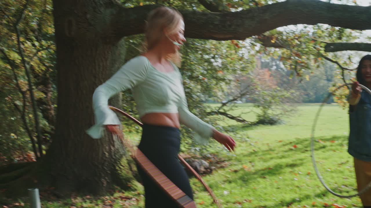 Two women hula hooping in a park