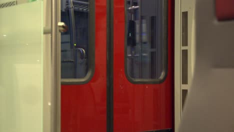 red transit train doors and passing night scenery through windows