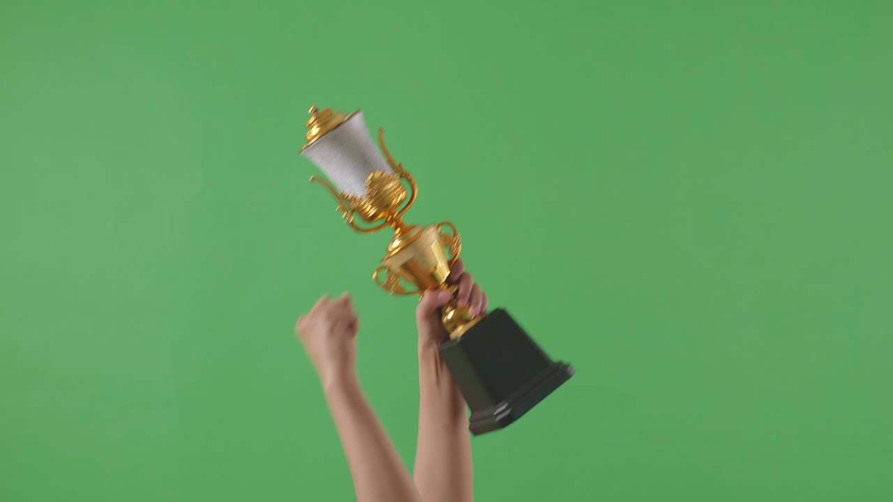 las manos levantadas de una mujer están sosteniendo un trofeo. fondo de pantalla verde
