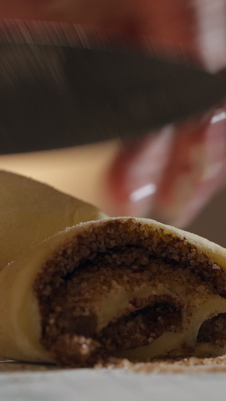 Pastry Chef Slicing Raw Cinnamon Rolls With Knife. - vertical shot