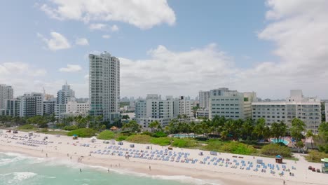 forwards fly above beach on sea coast in tropical vacation resort. revealing skyline with downtown skyscrapers. miami, usa
