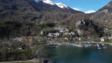 Clip-De-Drone-Que-Muestra-Lentamente-Un-Pintoresco-Pueblo-Junto-A-Un-Lago-En-Los-Alpes-Suizos