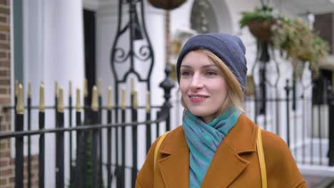 feliz alegre positiva y relajada joven mujer caucásica disfrutando del tiempo, caminando por una calle de londres y sonriendo mientras mira a su alrededor