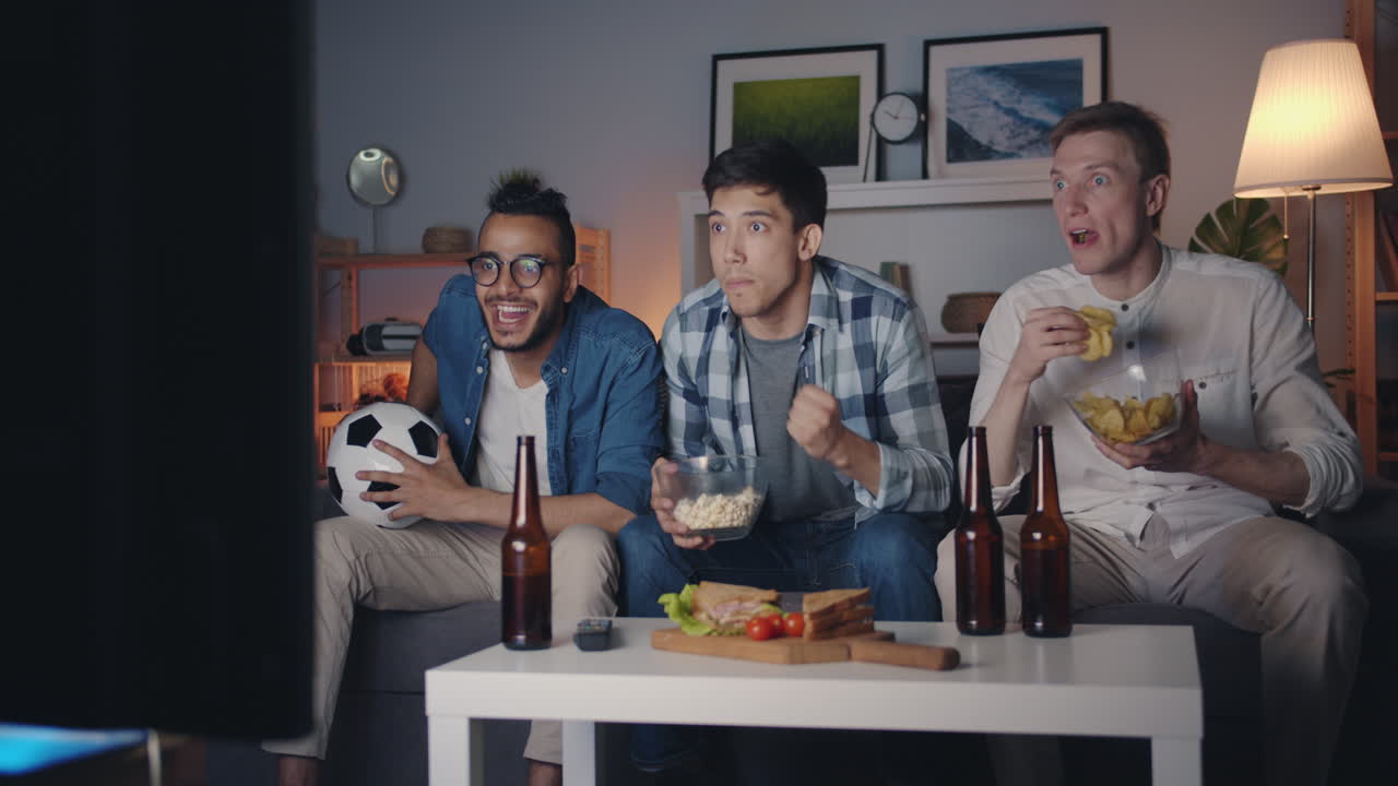 친구 들 이 집 에서 축구 경기 를 보고 있다