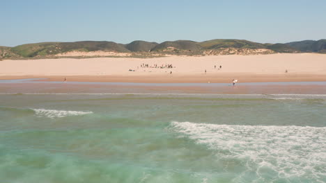 aerial: surfing the beach of bordeira in the algarve, portugal