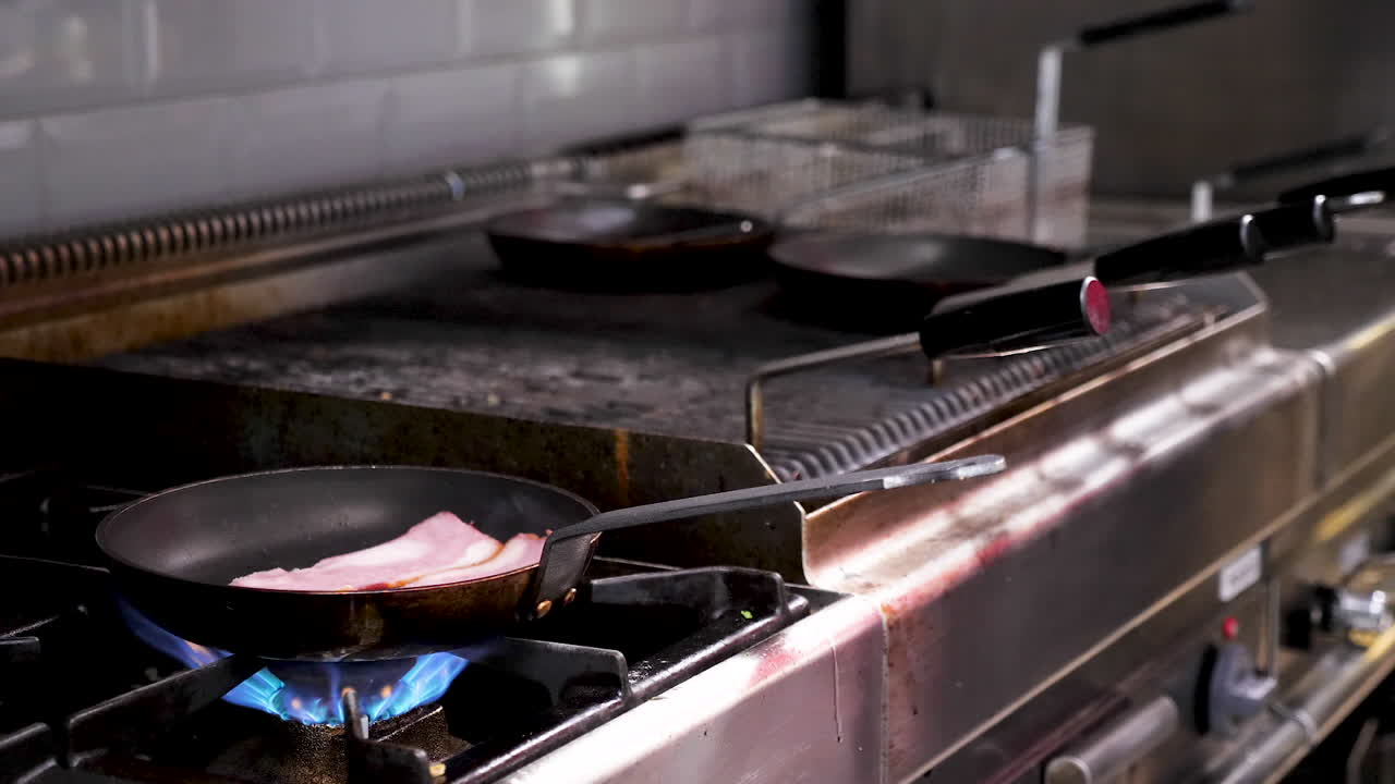 Bacon being cooked in a pan on a gas stove