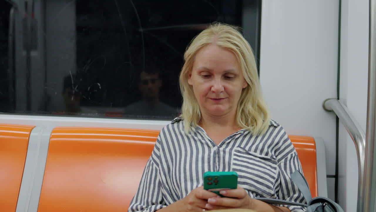 Kvinne bruker smarttelefon mens hun sitter på T-banen, konsept for urban pendling og moderne livsstil