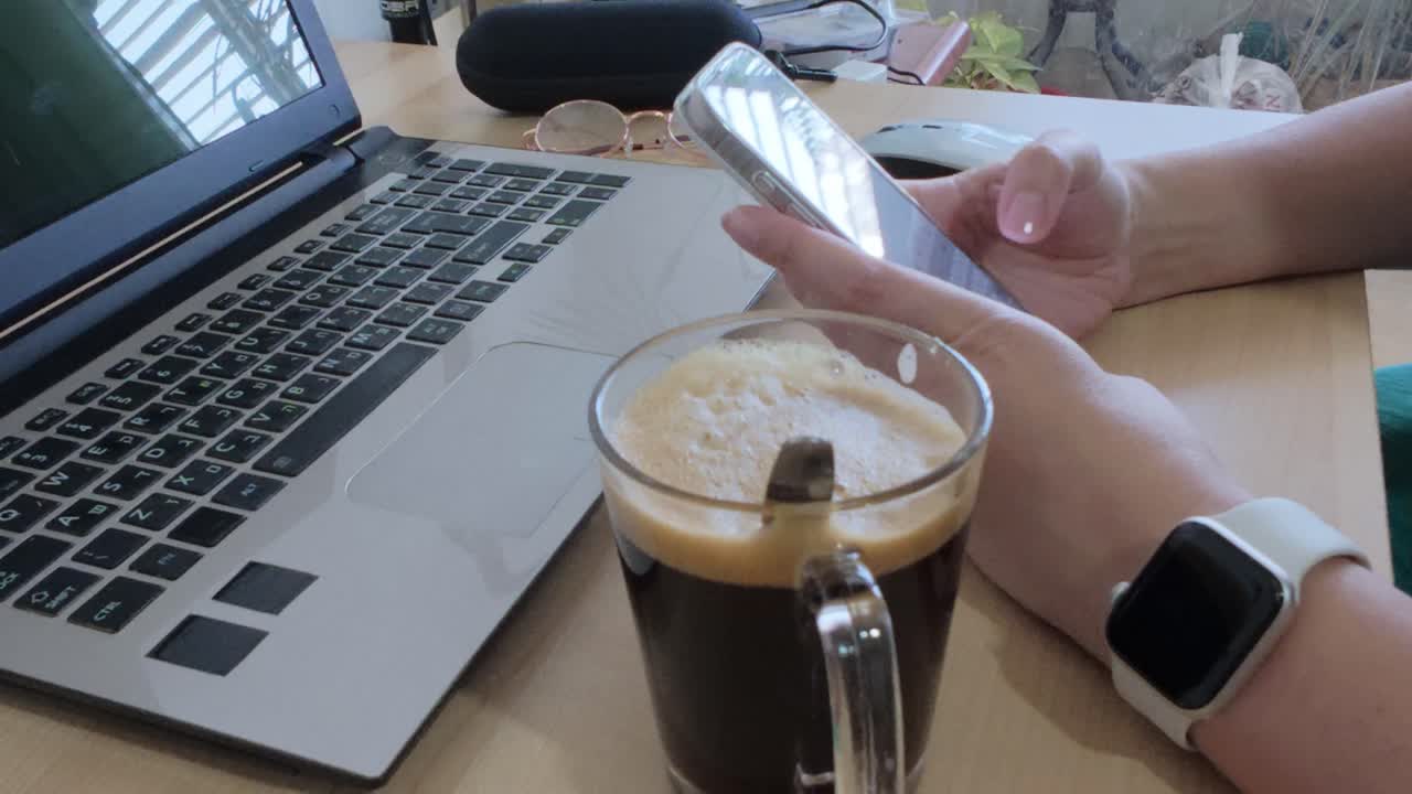 Person engaged in digital communication using a smartphone at their work desk