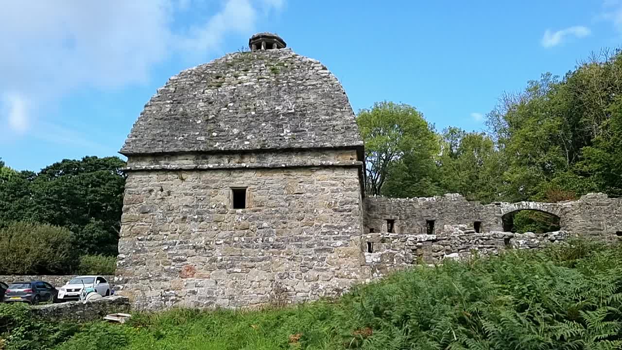 Antica colombaia in pietra di Penmon su terreni appartati della campagna gallese coperti di felci.