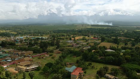 aerial view over a town towards burning fields of rural sunny africa - drone shot