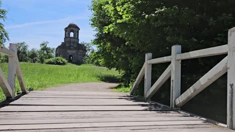 Statische-Aufnahme-Einer-Alten-Weißen-Holzbrücke-Mit-Grasfeld-Und-Altem-Gebäude-Im-Hintergrund,-Schwetzingen,-Deutschland