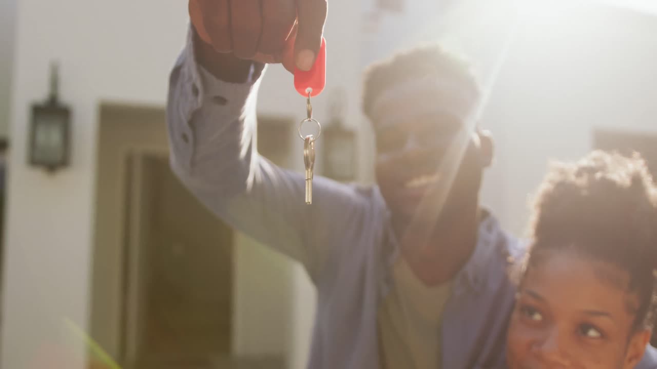 video de una feliz pareja afroamericana abrazándose y mostrando las llaves de una nueva casa