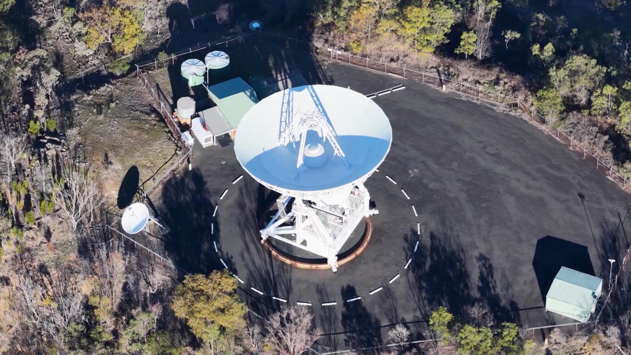Korkealta otettu ilmakuva valkoisesta satelliittiantennista Siding Springin observatoriossa, Australiassa.