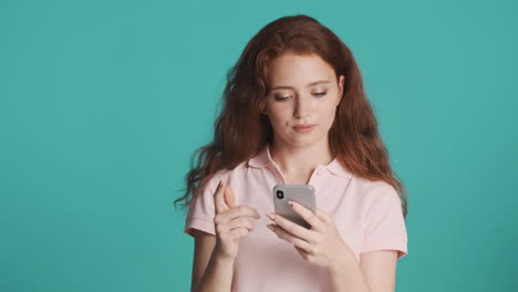 Redheaded-girl-in-front-of-camera-on-turquoise-background.