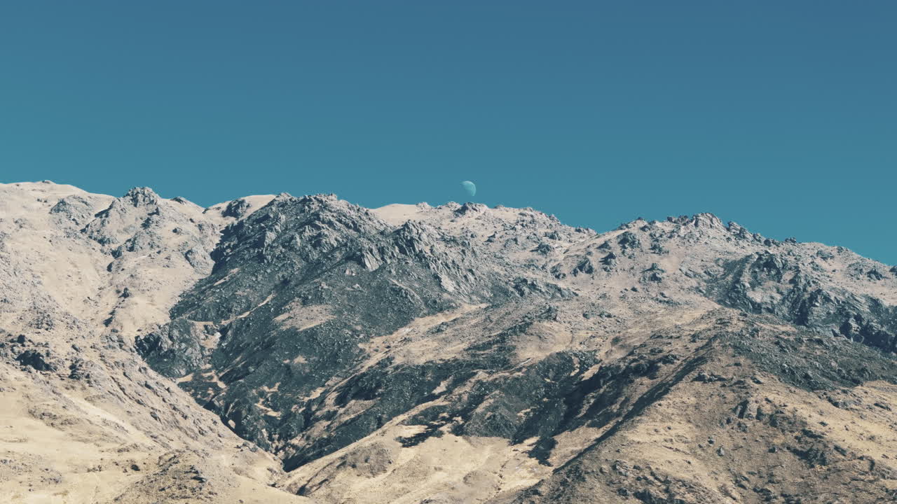 Moonrise over rugged Andean mountain peaks in a clear blue sky. Tafí del Valle, Tucumán, Argentina.