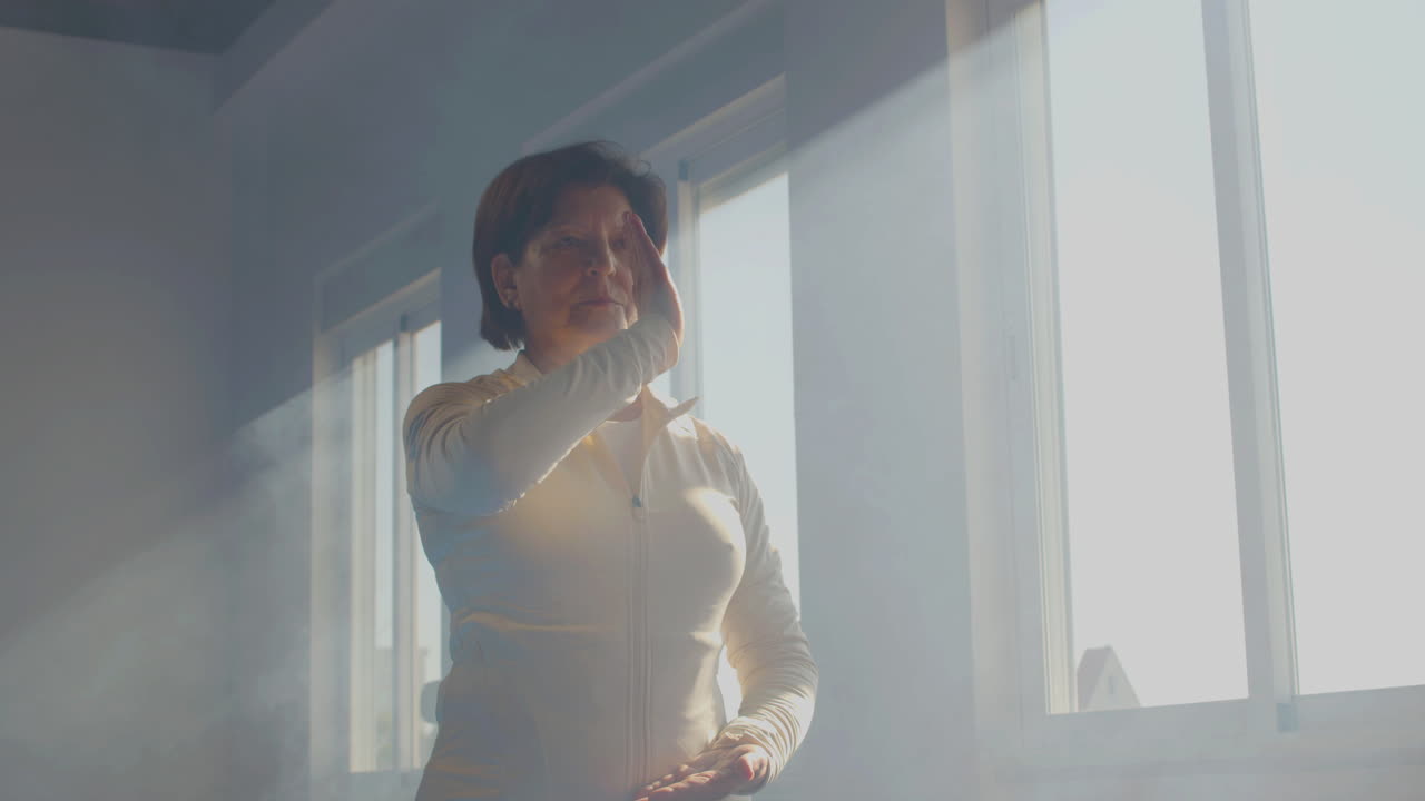 mujer mayor enfocada practicando tai chi gimnasia en el gimnasio