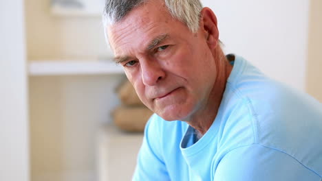 Unhappy-senior-man-sitting-on-his-bed