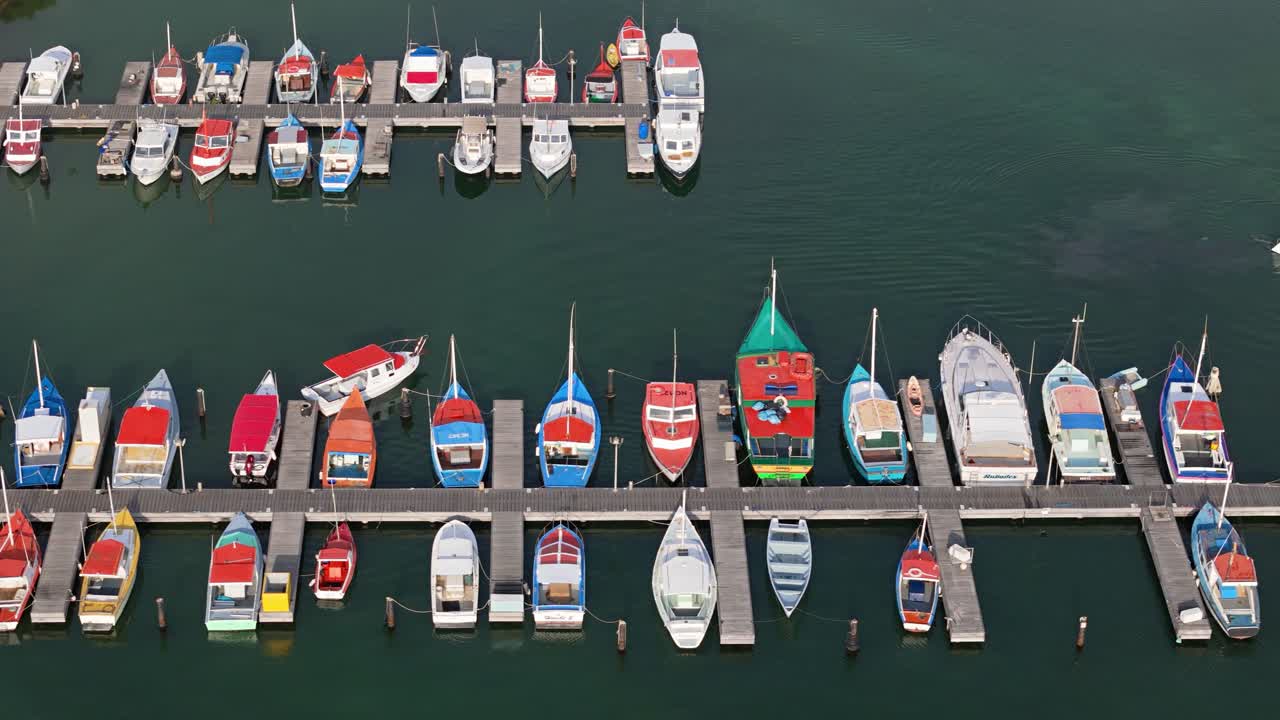 Drone bird's eye view pan across colorful boats docked at fishing harbor pier in Caribbean