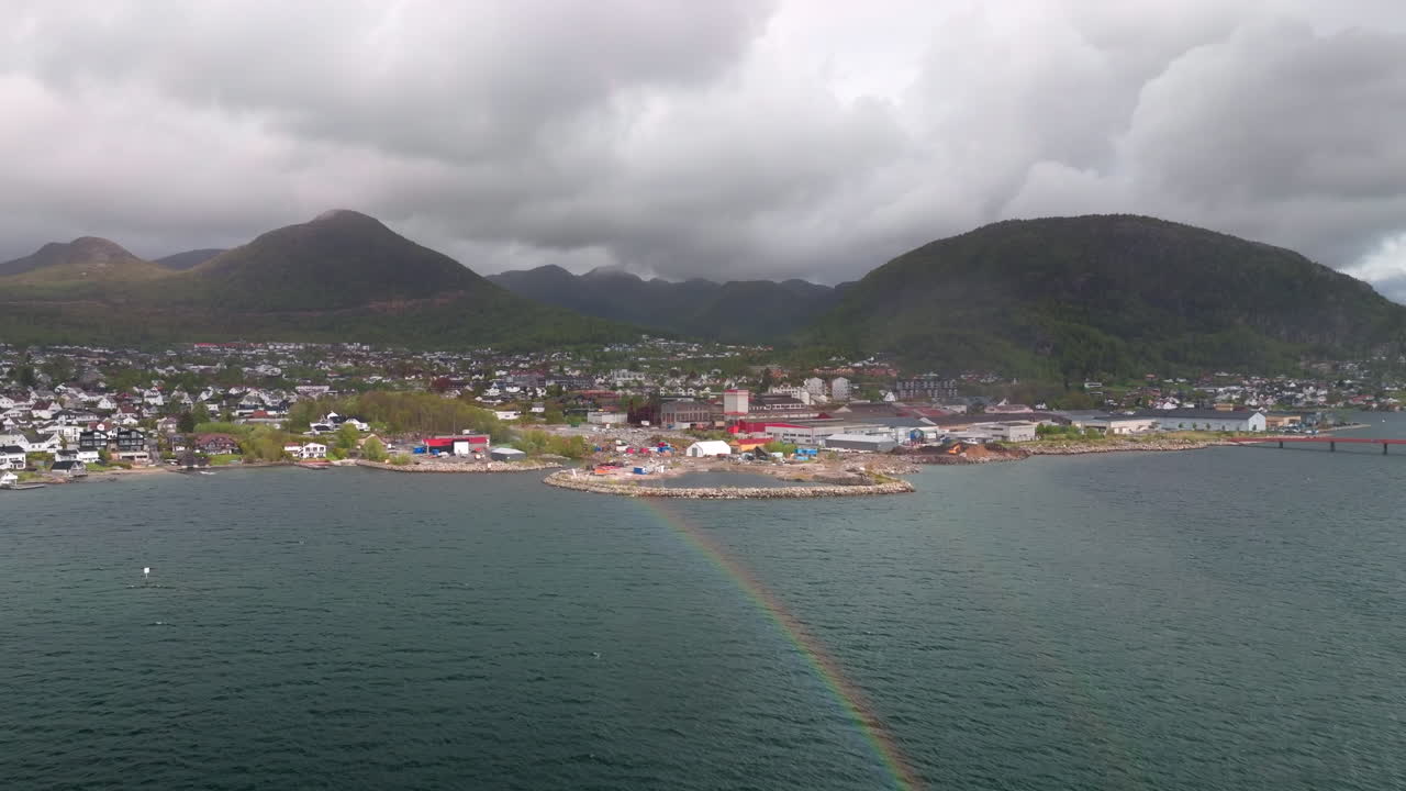 Aerial view of Jørpeland, Norway, showing the coastal town, mountains, and storm clouds over the scenic Nordic landscape