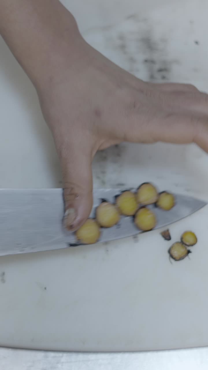 Hands slicing a dark vegetable on a cutting board