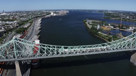 aerial view of the jacques cartier bridge in montreal, spanning the st. lawrence river. its iconic design and connection between the island and the south shore, with the city skyline in the backdrop.