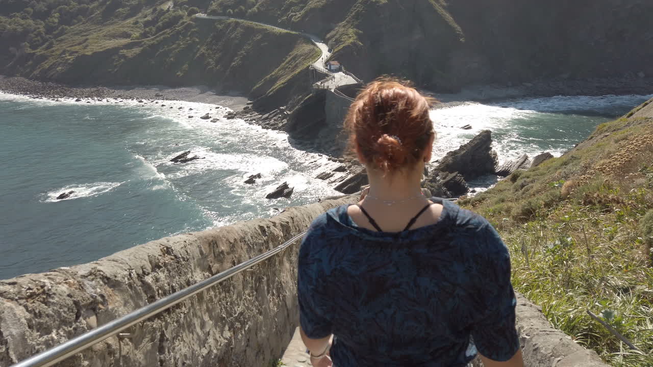 Woman walking on the bridge to Gaztelugatxe