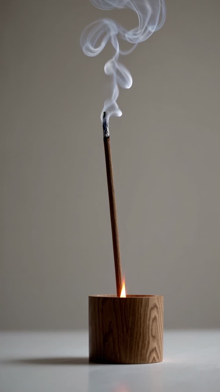 Concepto de vídeo minimalista con un primer plano de incienso quemándose en un soporte de madera