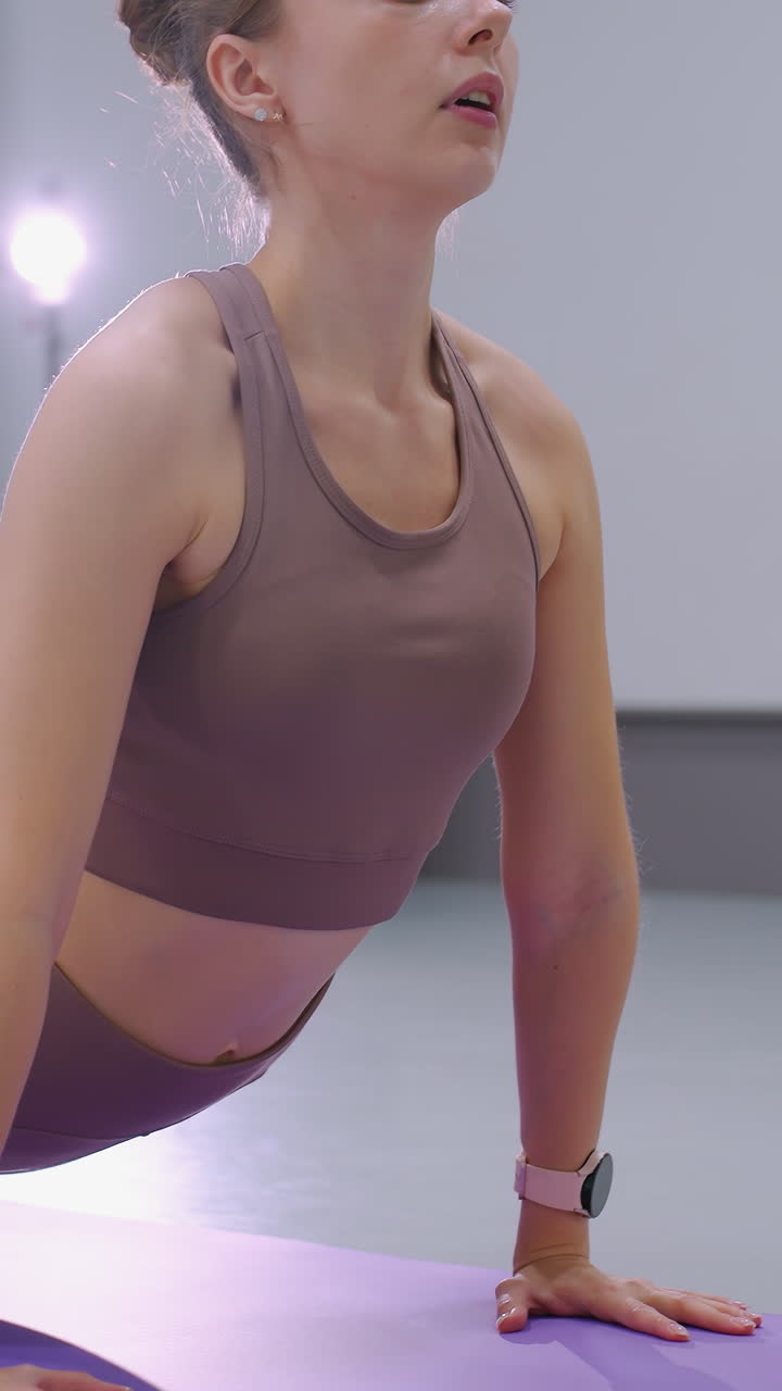 el atleta se dedica a un estiramiento profundo en una alfombra púrpura en un gimnasio moderno, con una iluminación suave que se refleja en el fondo, la flexibilidad de la aptitud y el enfoque enfatizados en esta postura de entrenamiento