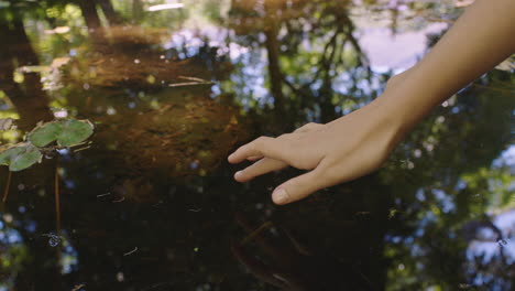 Frauenhand-Berührt-Das-Wasser-Im-Teich-Mit-Dem-Finger-Und-Erzeugt-Wellen