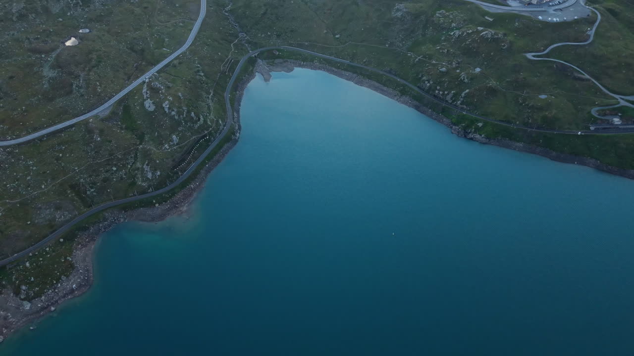 Aerial view of serene Swiss Alps lake and winding roads at twilight