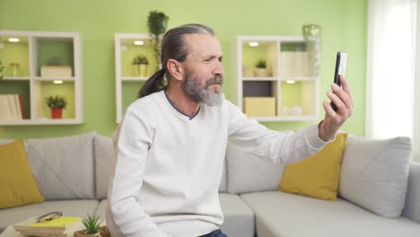 hombre de mediana edad videollamada en el teléfono inteligente en casa.