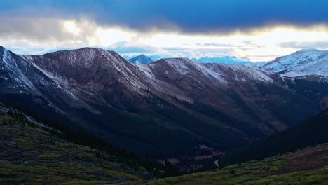 aerial view of a winding road cutting through vast green meadows with towering peaks in the distance at independence pass