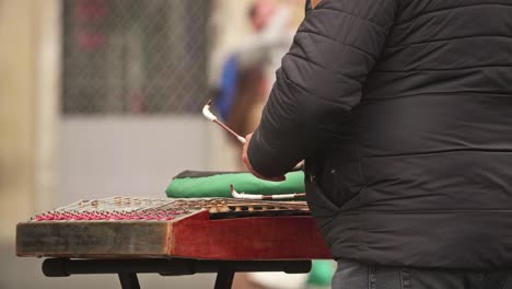 músico callejero tocando un martillo dulcimer