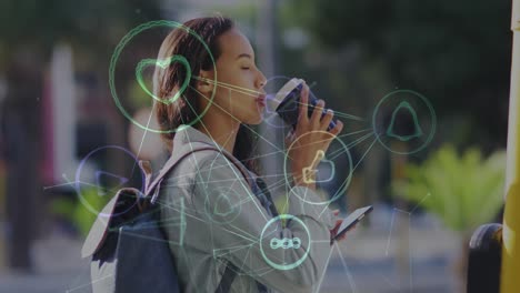 animation of network of social media icons over happy biracial woman drinking coffee in street
