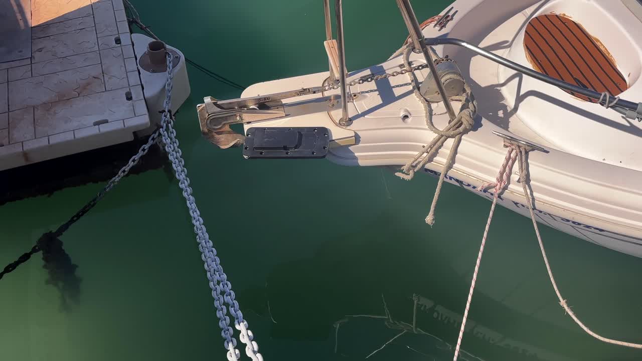 Close up of a boat’s bow gently moving on still waters with anchor chains