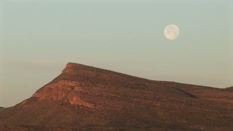 mediumshot of the moon hovering over a rocky landscape