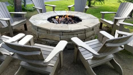 circular stone fire pit surrounded by empty adirondack chairs