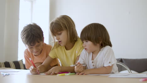 niños felices pintando con marcadores en la sala de estar