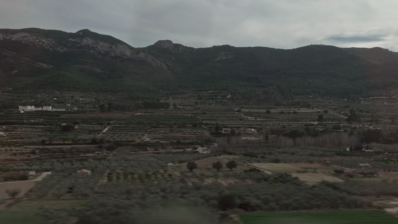 paisaje verde con montañas y tierras de cultivo en la ventana del tren