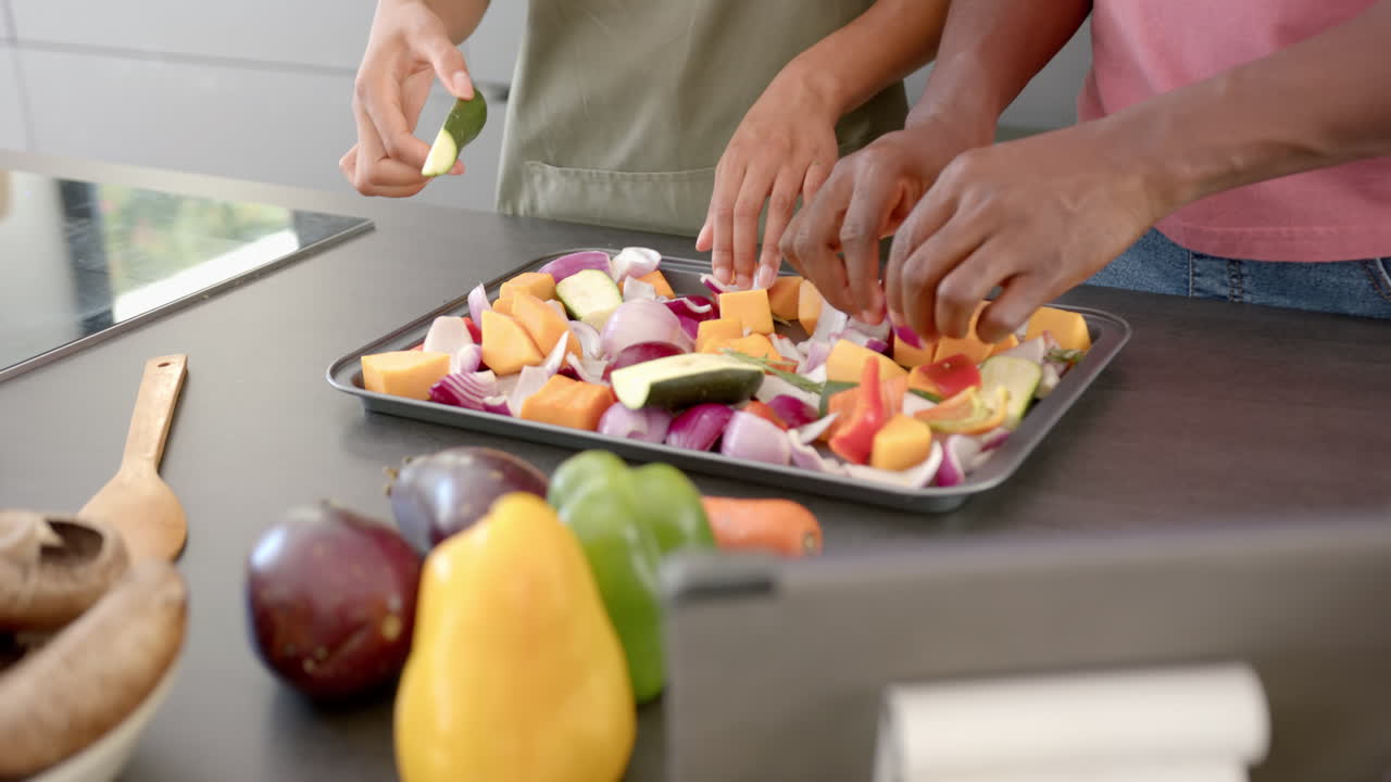 Preparing vegetables on baking tray, couple cooking together in kitchen