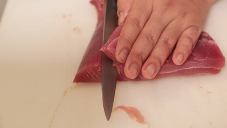 japanese chef slicing raw tuna with a knife for sushi preparation