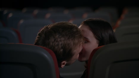 young guy and girl indulge in passion in cinema after film. kissing couple